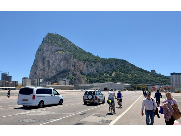 The Rock of Gibraltar is seen in the background as people and cars cross over the Gibraltar airport runway after crossing the border between Spain and the British territory of Gibraltar on May 5, 2022. (Photo by Daniel SLIM / AFP)