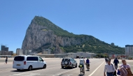 The Rock of Gibraltar is seen in the background as people and cars cross over the Gibraltar airport runway after crossing the border between Spain and the British territory of Gibraltar on May 5, 2022. (Photo by Daniel SLIM / AFP)
