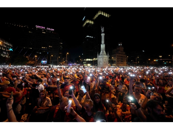 Spain's supporters turn on their phone flashlight as they watch the 2026 World Cup final match between Spain and Argentina displayed on giant screens underneath the Christopher Columbus statue on Colon square's in Madrid, on July 19, 2026. (Photo by Paul Hanna / AFP)