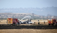 Fire crews spray down the wreckage of a US Marines’ F-35B fighter jet after it crashed into a field near Miramar Air Base in San Diego, California, on July 31, 2026.(Photo by SANDY HUFFAKER / AFP)