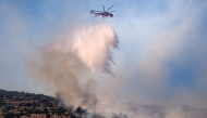 A firefighting helicopter drops water on a wildfire in Haidari, a suburb west of Athens, on July 31, 2026. (Photo by Aris Oikonomou / AFP)
