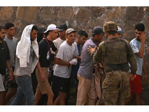 A Spanish soldier controls a group of migrants on their way back towards the Moroccan border, following their illegal crossing into the Spanish enclave of Ceuta, on August 1, 2026 (Photo by JORGE GUERRERO / AFP)