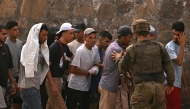 A Spanish soldier controls a group of migrants on their way back towards the Moroccan border, following their illegal crossing into the Spanish enclave of Ceuta, on August 1, 2026 (Photo by JORGE GUERRERO / AFP)