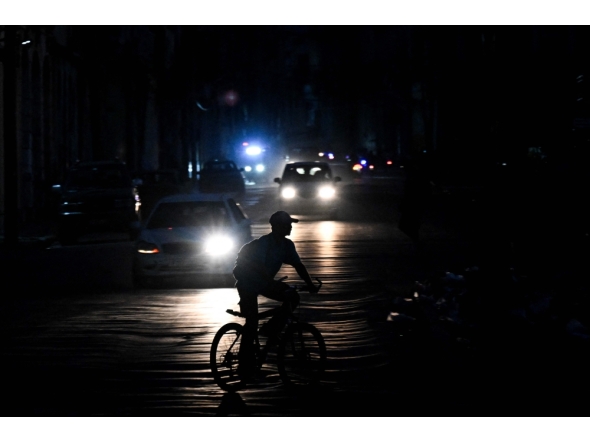 A man rides his bicycle down a street during a blackout in Havana on August 1, 2026. (Photo by Yamil Lage / AFP)