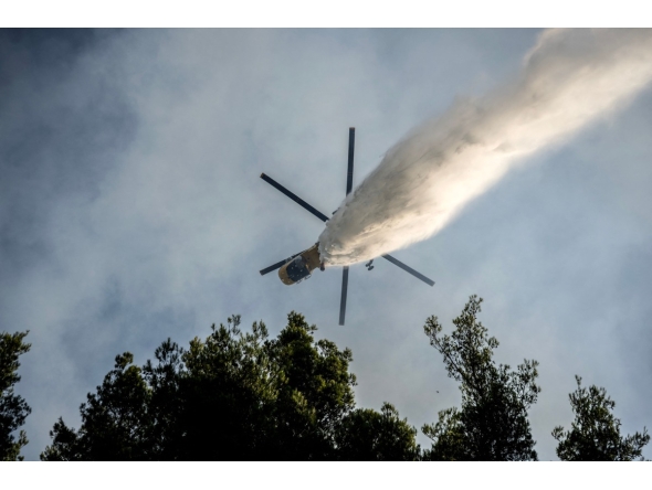 A firefighting helicopter drops water over a wildfire in the area of Porto Germeno, some 70 kilometres (45 miles) northwest of Athens in the region of Viotia, on August 2, 2026. (Photo by Angelos TZORTZINIS / AFP)