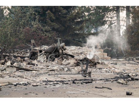 A burned motorcycle sits in the ashes of burned out residential home in the Balboa neighborhood of Spokane, Washington, on August 2, 2026. (Photo by Erick Doxey / AFP)
 