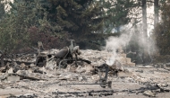 A burned motorcycle sits in the ashes of burned out residential home in the Balboa neighborhood of Spokane, Washington, on August 2, 2026. (Photo by Erick Doxey / AFP)
 