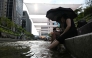 People cool off below sunshades over the Cheonggyecheon Stream in Seoul on August 3, 2026. (Photo by Greg Baker / AFP)