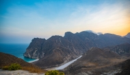 A photo of a beach, sea, and mountains in Oman