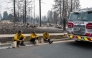 Three members of the Spokane Fire Department sit on a curb in front of burned out residential homes in the Balboa neighborhood of Spokane, Washington, on August 2, 2026. (Photo by Erick Doxey / AFP)