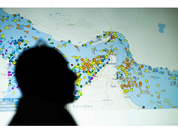 (Files) A photo illustration taken in Nicosia on May 4, 2026, shows a person in front of a large screen displaying vessel movements in the Strait of Hormuz on a ship-tracking website. (Photo by AFP)