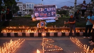 Mourners light candles before the portraits of mountaineer Nirmal Purja and his companions, who were killed in an avalanche in Pakistan, during a memorial ceremony in Kathmandu on August 4, 2026. (Photo by Prakash MATHEMA / AFP)