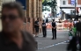 Police community support officers (PCSOs) speak to a person near cordon tape at Endell road in covent garden, central London on August 5, 2026. Photo by Henry NICHOLLS / AFP
