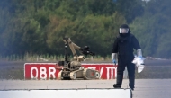 A forensic technician is at work alongside a bomb disposal robot near a Ukrainian cargo plane at Leipzig/Halle Airport in Schkeuditz, eastern Germany on August 5, 2026, after an explosives-laden drone was found near the plane overnight, and another aircraft collided with an unknown flying object mid-air nearby before landing safely. Photo by Hendrik Schmidt / dpa / AFP