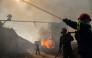 Firemen work to extinguish a fire that broke out at a livestock facility near Kouvaras, south of Athens, on August 10, 2026. (Photo by Aris MESSINIS / AFP)
