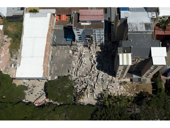 This aerial view shows rescuers searching for survivors amid the rubble of a collapsed building after an earthquake in Cali, Colombia on August 11, 2026. (Photo by JOAQUIN SARMIENTO / AFP)