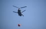 A Royal Netherlands Air Force Boeing CH-47D Chinook carrying a bambi bucket departs from Baelen, near Eupen, eastern Belgium to tackle a wildfire burning in the Hautes Fagnes (High Fens) nature reserve on August 16, 2026. Photo by JOHN THYS / AFP