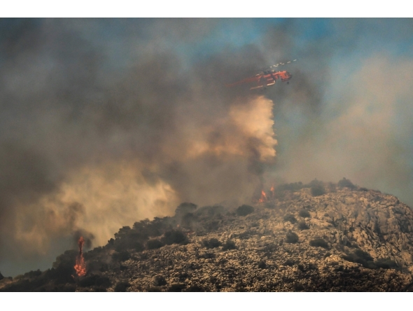 A firefighting helicopter drops water during a wildfire in the island of Salamina, near Athens, on August 16, 2026. (Photo by Yannis Panagopoulos / Eurokinissi / AFP)