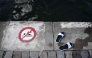 (FILES) This photograph shows sandals next to a sign indicating that swimming is forbidden, at the Bassin de la Villette during a cold water swimming event in Paris on March 29, 2025.(Photo by Thibaud MORITZ / AFP)