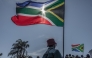 March and March Movement members wave South African flags as they protest outside the Durban International Convention Centre (ICC) under the theme 