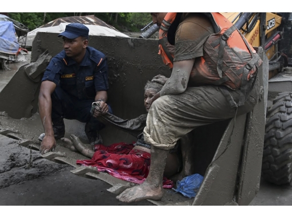 Rescue personnel use an excavator to carry a person affected by flash floods at Devghat in Nepal's Nuwakot district on August 26, 2026. (Photo by Prakash MATHEMA / AFP)