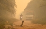 A dog sits in the middle of a haze-shrouded road caused by forest and land fires in Palangkaraya city, Central Kalimantan, on August 28, 2026. (Photo by REINA / AFP)