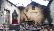 A woman inspects her damaged house after it was burned down in a forest fire in Bordj T'har, a town and commune in Algeria's northeastern Jijel Province, on August 27, 2026. (Photo by AFP)