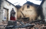A woman inspects her damaged house after it was burned down in a forest fire in Bordj T'har, a town and commune in Algeria's northeastern Jijel Province, on August 27, 2026. (Photo by AFP)