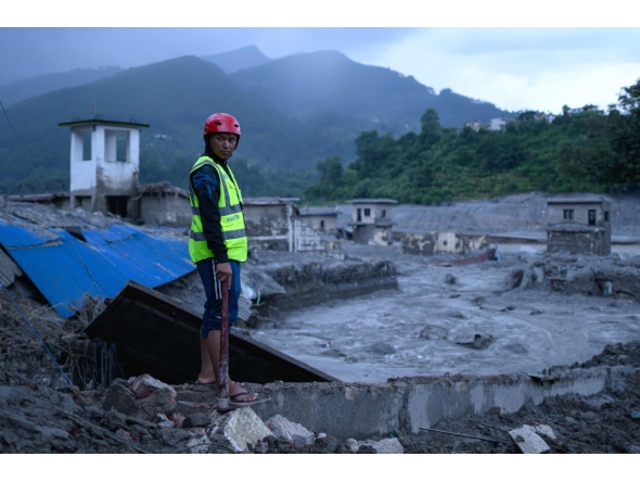 A disaster rescue personnel looks on at the site of damaged buildings in the aftermath of flash floods at Trishuli Bazar in Nepal's Nuwakot district on August 29, 2026. (Photo by MANAN VATSYAYANA / AFP)
