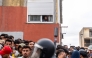 A resident watches from her window migrants waiting on the sidewalk before being registered in Loma Colmenar district of Ceuta on August 31, 2026. Photo by Antonio Sempere / AFP