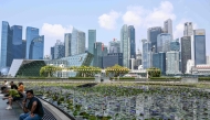 People sit next to a pond outside ArtScience museum at Marina bay in Singapore on September 8, 2026. (Photo by Roslan RAHMAN / AFP)