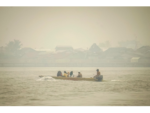 People travel on a river boat as thick haze from forest and land fires blankets Benua Melayu Darat village in Pontianak, West Kalimantan, on September 16, 2026. (Photo by DITO / AFP)