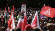 Workers wave flags of the industrial union IG Metall as they protest against job cuts in front of the commercial cars plant of German car maker Volkswagen (VW) on September 21, 2026 in Hanover, central Germany. (Photo by Ronny Hartmann / AFP)