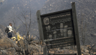 A sign for the Iguaque Fauna and Flora Sanctuary stands amid burned vegetation on San Marcos Hill following a forest fire in the municipality of Villa de Leyva, Boyaca department, Colombia, on September 20, 2026. (Photo by LUIS LIZARAZO / AFP)