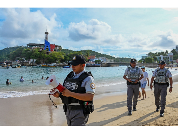 A member of the Mexican National Guard makes an announcement to residents and visitors about the approach of Hurricane Polo along a beach in Acapulco, Guerrero state, Mexico, on September 21, 2026.  (Photo by Francisco Robles / AFP)
