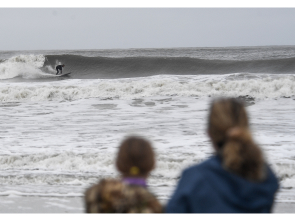 People watch a surfer ride the choppy waves in Ocean City, New Jersey, on September 26, 2026.  (Photo by Matthew HATCHER / AFP)