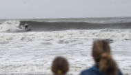 People watch a surfer ride the choppy waves in Ocean City, New Jersey, on September 26, 2026.  (Photo by Matthew HATCHER / AFP)