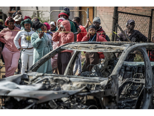 Residents stand behind police tape near the scene where gunmen armed with assault rifles stormed a bar in Johannesburg on September 27, 2026. Photo by EMMANUEL CROSET / AFP