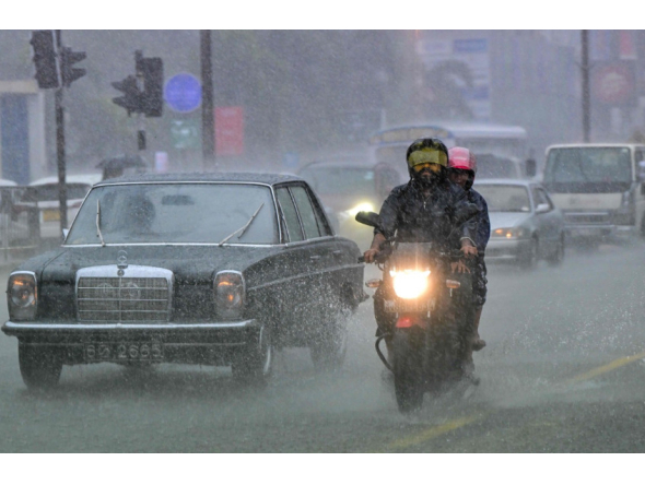File photo showing commuters driving down a flooded street in Colombo. AFP file photo.