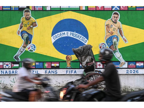 Motorcyclists ride past a graffiti featuring Brazilian football player Neymar (L) and Raphinha ahead of a FIFA international friendly football match between India and Brazil in Kolkata on September 29, 2026. (Photo by Dibyangshu Sarkar / AFP)
