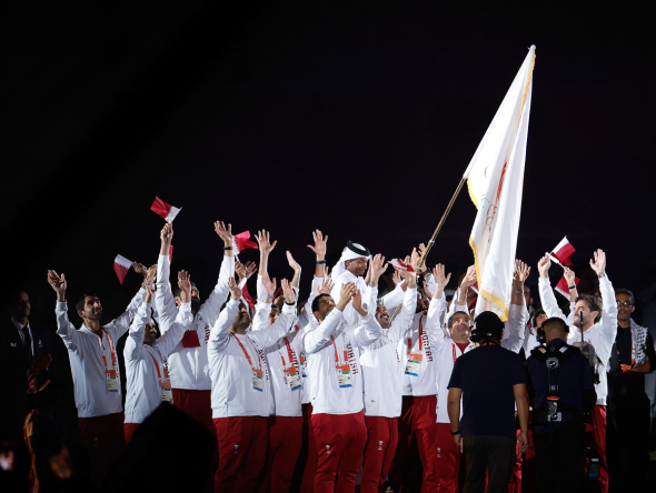 Members of the Qatar delegation celebrate as high jump legend Mutaz Barshim carries the OCA flag during the closing ceremony. (Xinhua)