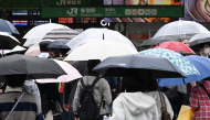Pedestrians cross a road using umbrellas at the Shinjuku district in Tokyo on September 29, 2026, as strong Typhoon Surigae approaches Japan. (Photo by Toshifumi KITAMURA / AFP)
