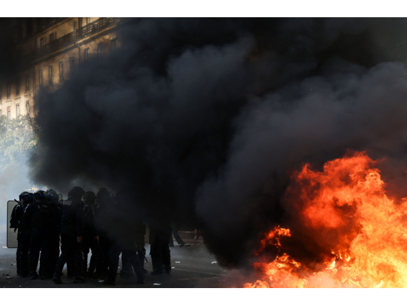Police officers stand guard by bins and furniture set on fire in the street during a demonstration of high-school students, in Paris on October 6, 2026, as part of a nationwide protest movement over learning conditions. (Photo by Kenzo TRIBOUILLARD / AFP)
