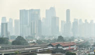 A dense layer of haze blankets the Kuala Lumpur skyline as a light rail train passes through the city on October 7, 2026.  (Photo by Arif Kartono / AFP)
