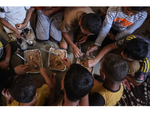 This photo taken on October 6, 2026, shows the children of Nihaya Al-Masri, sharing a meal provided by a charity kitchen in Khan Yunis, in the southern Gaza Strip. (Photo by Bashar Taleb / AFP)