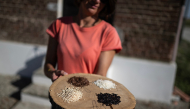 Alice Cerutti, owner of Cascina Oschiena, holds a tray displaying four different types of rice at the farm in the countryside of Crova, near Vercelli, northwestern Italy on September 28, 2026. Photo by Marco Bertorello / AFP