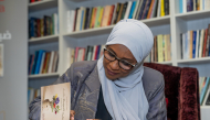 Aisha Al-Idrissi signs a copy of her book for a visitor.