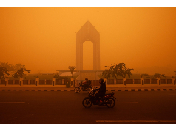 Motorcyclists ride in the morning in Palangkaraya, Central Kalimantan on October 14, 2026, amid thick haze from forest and land fires in the region. (Photo by Reina / AFP)