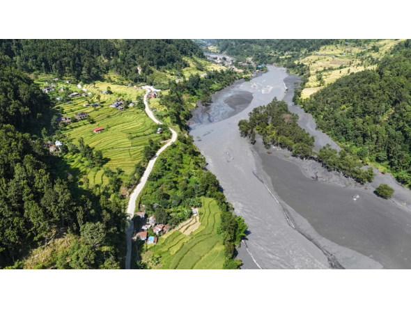 An aerial view shows muddy water flowing through the Budhi Gandaki river, separating Nepal's Gorkha (L) and Dhading districts on October 14, 2026, in the aftermath of a flash flood caused by a dry landslide. (Photo by Prakash Mathema / AFP)