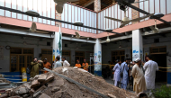 People gather around debris and rubble lying in the courtyard of a school following a roof collapse, in Peshawar on October 15, 2026. Photo by Abdul MAJEED / AFP
